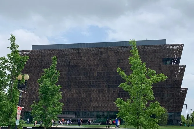 The museum's tiered bronze facade behind young trees on the National Mall